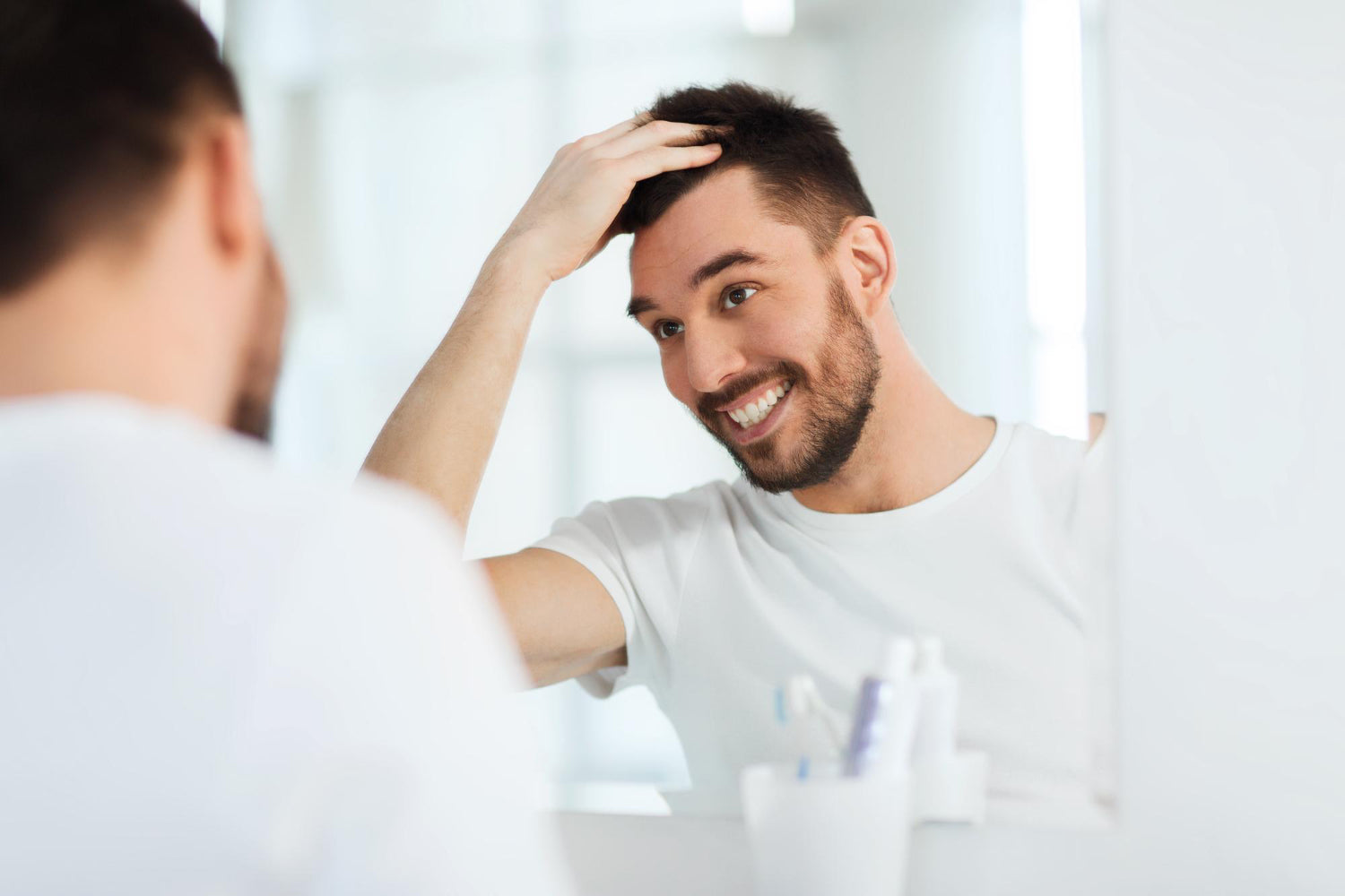 files/beauty-hygiene-hairstyle-people-concept-smiling-young-man-looking-mirror-styling-hair-home-bathroom.jpg